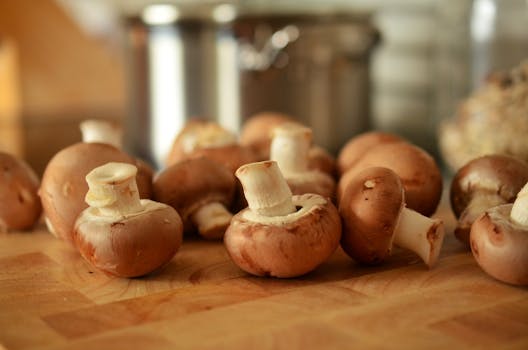 Close-up of fresh brown mushrooms on a wooden cutting board in a kitchen setting.